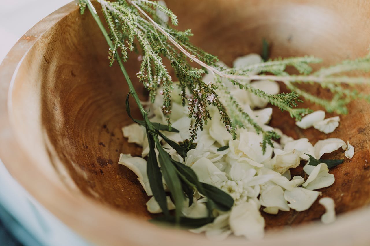 Wooden bowl filled with fresh herbs and flowers for aromatherapy and relaxation.